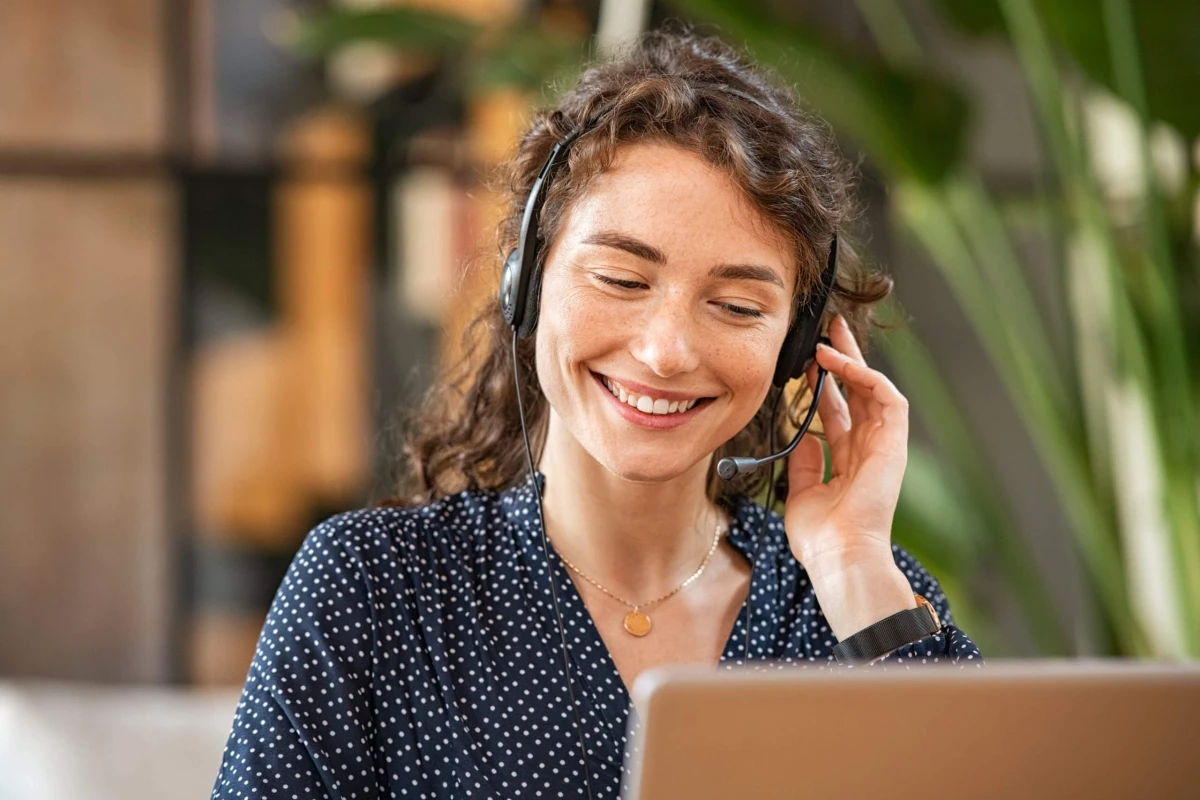 Happy,Young,Woman,Working,On,Laptop,While,Talking,To,Customer
